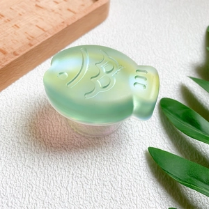 Macro detail of a 3D laser-etched fish design on a mint green collapsible phone stand