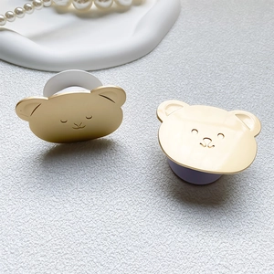 Detailed macro view of cute bear phone stands in glossy gold and matte finishes