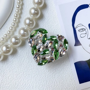 Macro detail of luxury heart phone grip with green and clear rhinestones