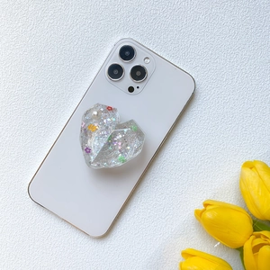 Sparkly heart shaped resin phone grip with stars and flowers on white smartphone