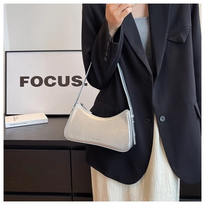 Macro detail of silver mirror finish crescent bag with subtle leather texture and logo