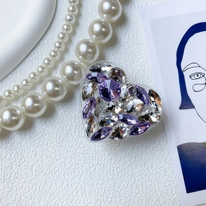 Macro shot of luxury heart phone grip with purple crystals on white leather background