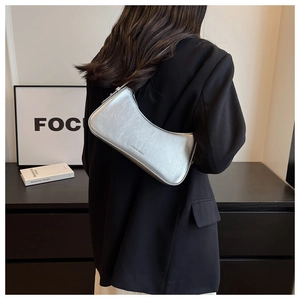 Detail view of a matte silver crescent shoulder bag featuring fine leather texture and zipper