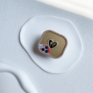 Luxury heart rhinestone mirror phone socket grip with bow and pearl detail on a white plate