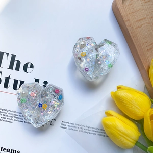Detail of a sparkling heart phone grip with silver glitter, colorful flowers, and pearls