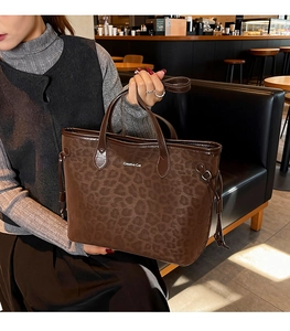 Detail of leopard print tote bag with Creative Cat text in a cozy cafe setting