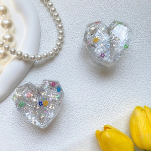 Macro detail of heart-shaped phone grip with silver glitter, flowers, and pearl inlay