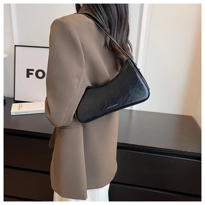 Model view of a black leather hobo bag showing its sleek half-moon shape and shoulder strap