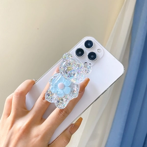 Glitzernder Bär Handyhalter mit blauer Blume auf weißem Smartphone als Ständer
