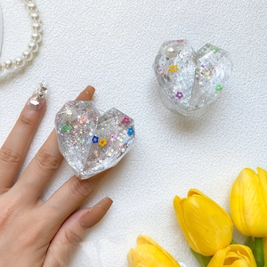 Detail of heart-shaped resin phone grip with glitter, embedded flowers and pearls
