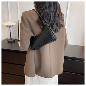 Minimalist black leather underarm bag styled with a brown blazer for a chic fashion look