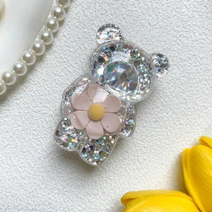 Makroaufnahme von Bären-Handyhalterung mit holografischem Glitzer und rosa Blume