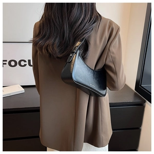Detail view of the sleek black leather underarm bag with an adjustable metal buckle