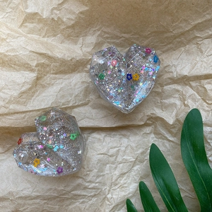 Detailed view of two heart-shaped glitter phone grips with pearls and colorful sequins