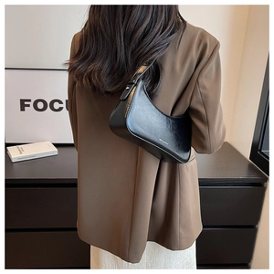 Chic black crescent underarm bag shown in a minimalist urban setting worn by a model