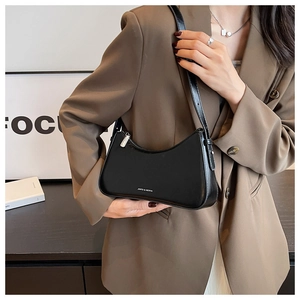 Detail of black leather crescent bag with silver zipper and logo by a model in a blazer