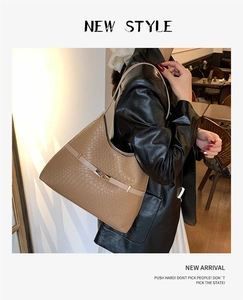 Detail of tan crocodile texture shoulder bag with light straps and metal buckle closure