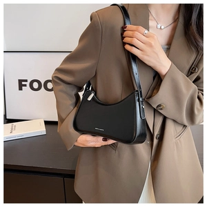 Close-up of black polished leather crescent shoulder bag with silver zip and logo