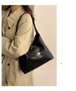 Detail of black woven leather shoulder bag with gold buckle on trench coat model