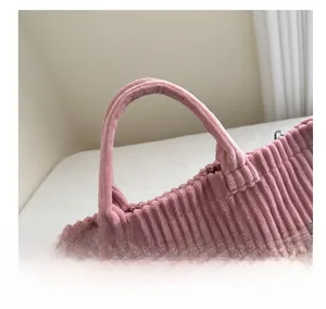 Detail of pink corduroy tote bag featuring soft handle, silver metal D-ring and BAG print