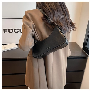 Close-up of sleek black leather shoulder bag with silver logo and polished texture