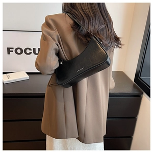 Detail showing back view of black glossy leather hobo bag with sleek shoulder strap
