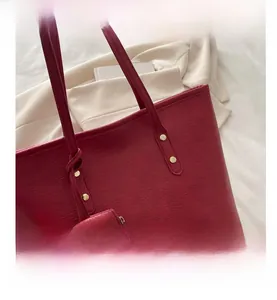 Macro view of large red tote bag with gold stud hardware and matching pouch detail