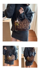 Detail view of leopard print bucket bag featuring brown leather trim and bear charm