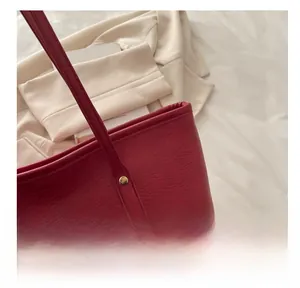 Close-up of textured red leather shoulder bag with metal rivet reinforcement details