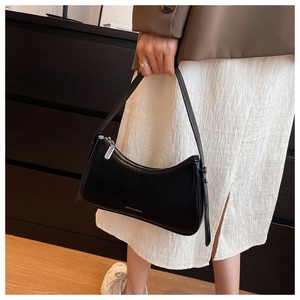 Detail shot of black faux leather underarm bag with silver zipper and white logo text