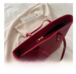 Close-up of smooth gold zipper and pebble leather texture on large red tote bag