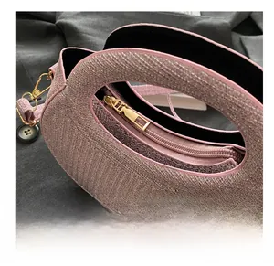Détail du sac à main rose tissé avec fermeture éclair dorée et poignée creuse design