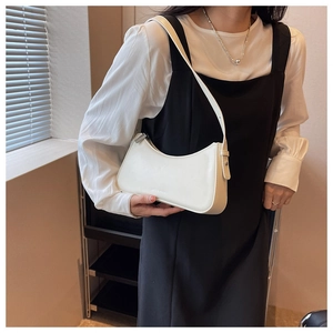 Close-up of minimalist white leather baguette bag with silver zipper and brand embossing