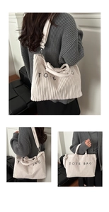 Detail of white corduroy tote bag showing ribbed texture and adjustable shoulder strap