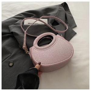 Detail of pink woven texture handbag with round handle and gold metal hardware