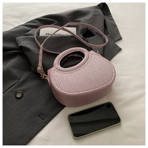 Sac à bandoulière violet à texture tissée posé près d'un blazer et de livres