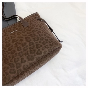 Close-up of leopard print tote bag with Creative Cat text and brown leather handle