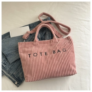 Close-up of pink corduroy tote bag featuring black embroidered lettering on soft fabric