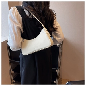 Shoulder shot of a creamy white crescent bag in smooth leather on a model's arm