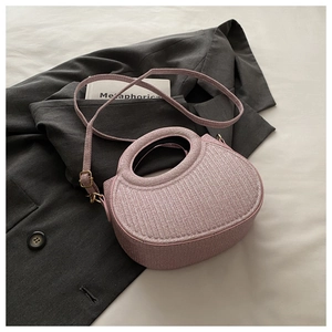 Detail of light pink woven textured crossbody bag on a grey blazer showing top handle