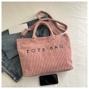 Close-up of pink corduroy tote bag featuring TOTE BAG embroidery and metal hardware details