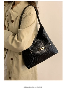 Detail of woven black leather texture and gold buckle on stylish hobo shoulder bag
