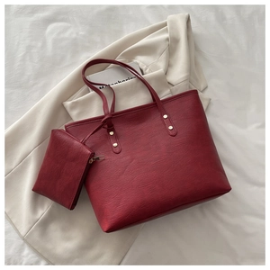 Deep red tote bag set with matching pouch and gold rivet details on white fabric