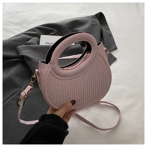 Detailed texture of pink woven semi-circular bag with golden ring handle and strap