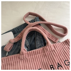 Macro detail of pink corduroy tote bag with black BAG embroidery and silver hardware