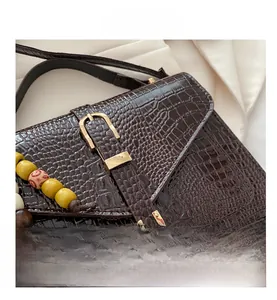 Macro shot of dark brown crocodile texture leather bag with gold buckle and beaded detail