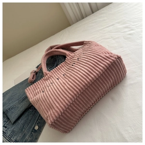 Detail of pink corduroy tote bag with textured stripes and black letter embroidery
