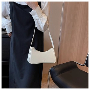 White crescent baguette bag shown on shoulder with minimalist fashion styling