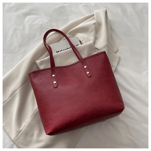 Detailed view of red leather tote bag with gold rivets and smooth texture for commuting