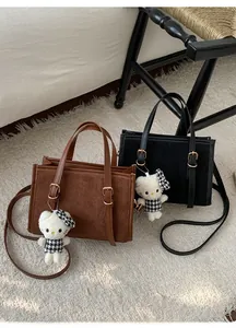 Dettaglio borsa retrò opaca con doppie fibbie e ciondolo di peluche carino